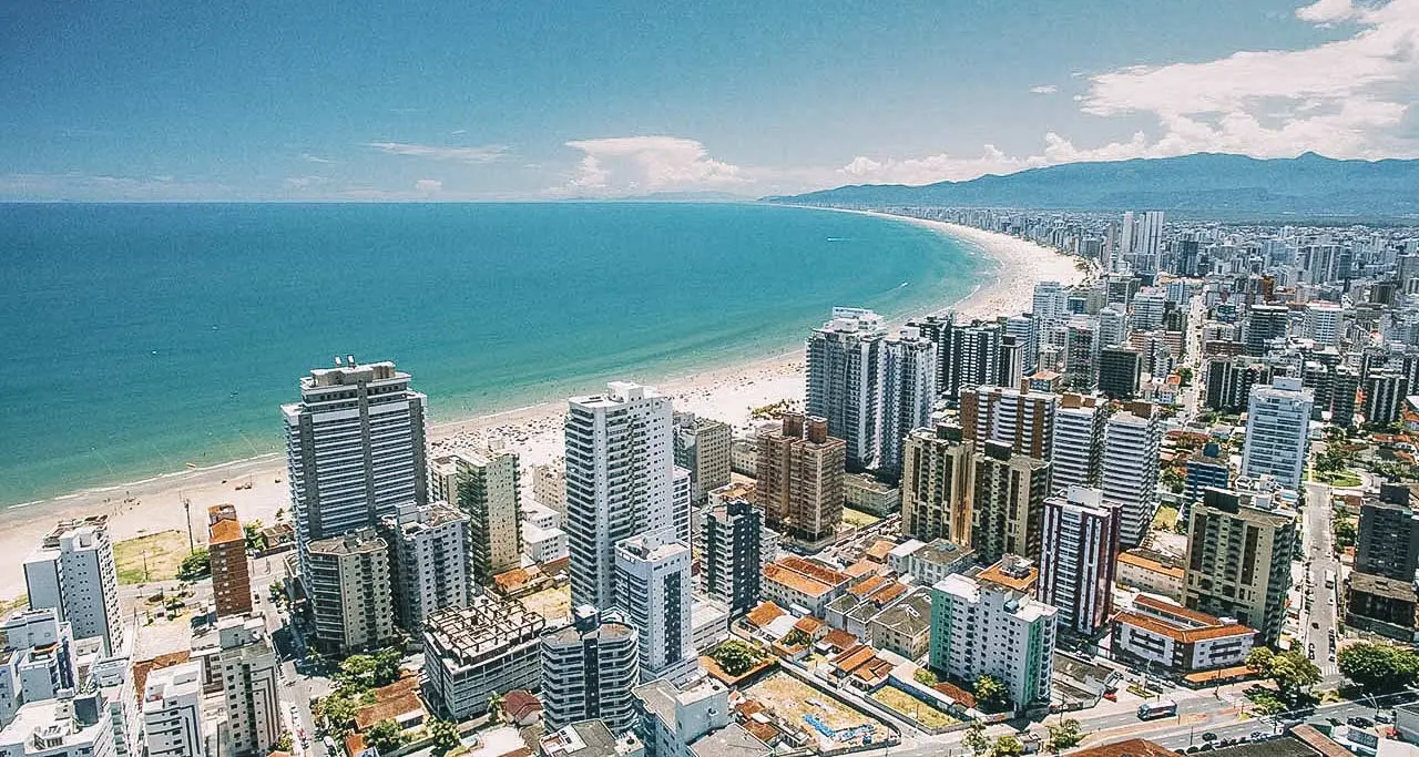 Ilustração moderna mostrando Praia Grande e um wireframe de site flutuando, representando tecnologia e negócios locais